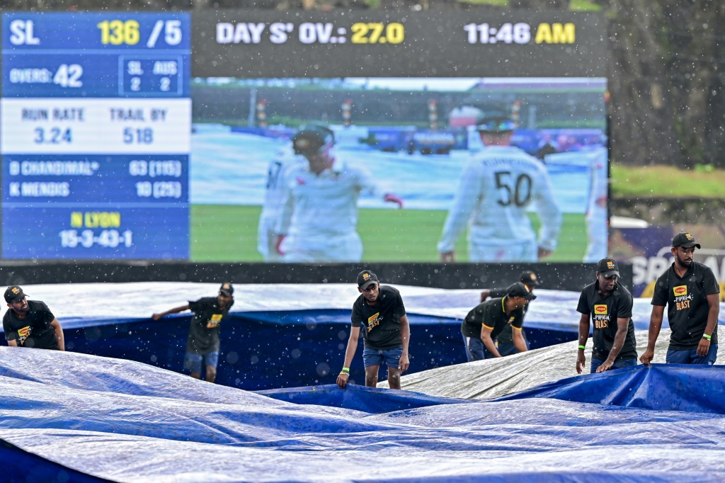 Groundsmen cover the field as rain halts play during the third day of the first Test between Sri Lanka and Australia in Galle, AFP